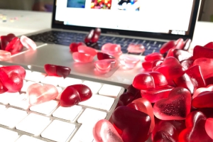 Fruchtgummi-Herzen liegen auf Laptop verteilt