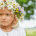 Glückliches blondes Mädchen mit Blumenkranz im weißen Hemd im Grünen
