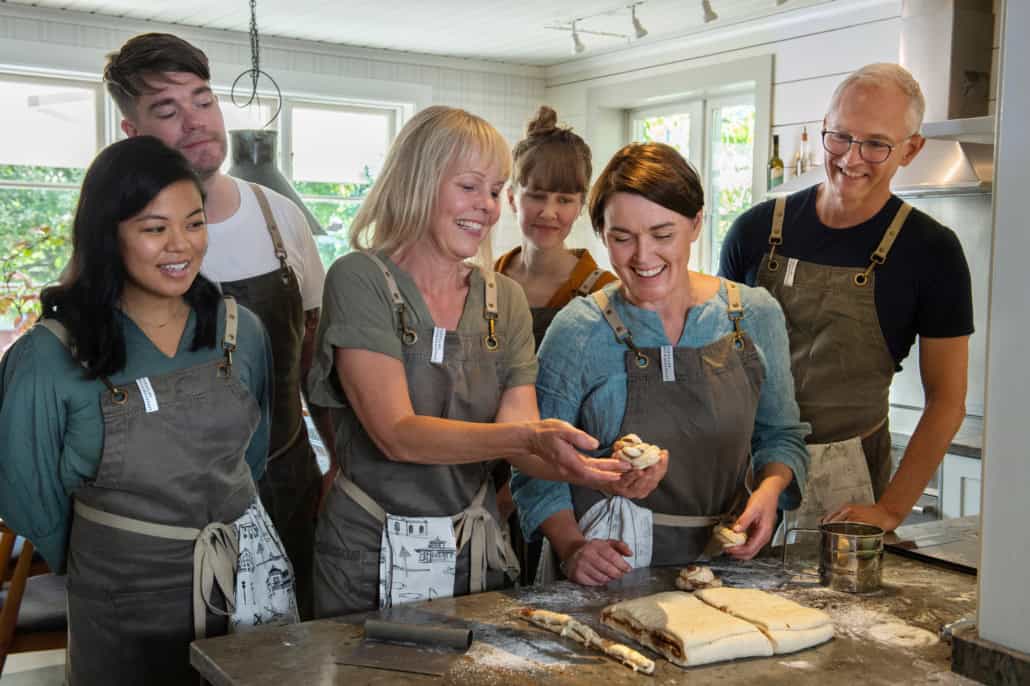 Lachende Menschen lernen Zimtschnecken backen